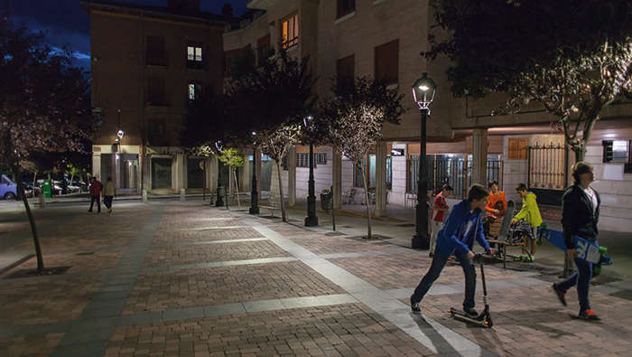 Des enfants jouant la nuit sur une place mise en lumière par Philips Lighting