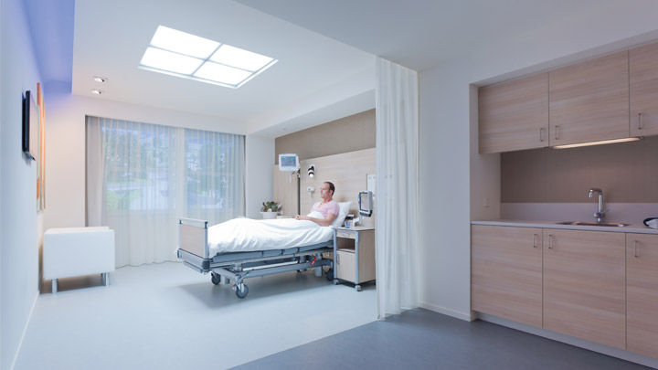 Nurse in softly lit room listing to patient’s heart with patient - hospital lighting