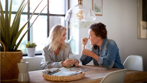 Deux femmes dans une maison qui parlent sous un luminaire doté d'une ampoule Philips