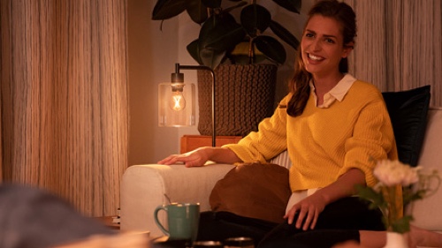 Une femme sur son divan à la maison profitant d'un éclairage tamisé