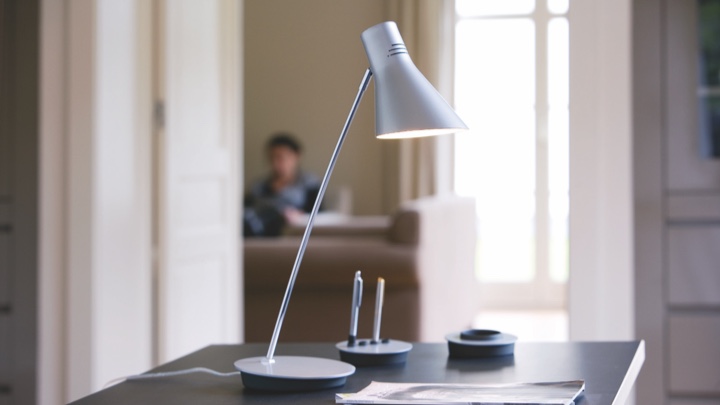 A table lamp on a desk aimed at paper and pen