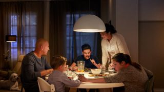 Large LED pendant light illuminates family dinner table, creating warm ambiance for evening meals and showcasing energy-efficient overhead lighting solutions for modern homes