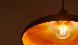 "Vintage-style LED filament bulb in pendant lamp, emitting warm golden glow, showcasing energy-efficient nostalgic lighting for cozy home ambiance."