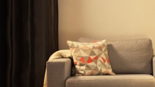 Salon confortable avec une lampe de table DEL moderne, illuminant une causeuse grise et créant une ambiance chaleureuse pour la détente à la maison.