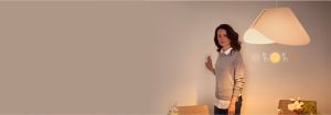 "Femme ajustant le gradateur intelligent, contrôlant l’ambiance d’éclairage DEL chaude dans l’espace de vie contemporain avec décor minimaliste"