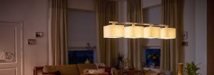 Une suspension DEL moderne avec plusieurs abat-jours en tissu illumine un salon confortable, présentant des solutions d'éclairage domestique écoénergétiques et élégantes pour un confort de soirée ambiant.