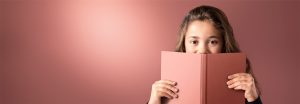 "Jeune fille jetant un coup d’œil sur un livre rose sur un fond doux éclairé par DEL, présentant un éclairage chaud et uniforme pour des environnements de lecture confortables. »