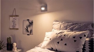 "Chambre élégante avec projecteur DEL réglable créant une ambiance confortable, éclairant la literie géométrique et un décor minimaliste."